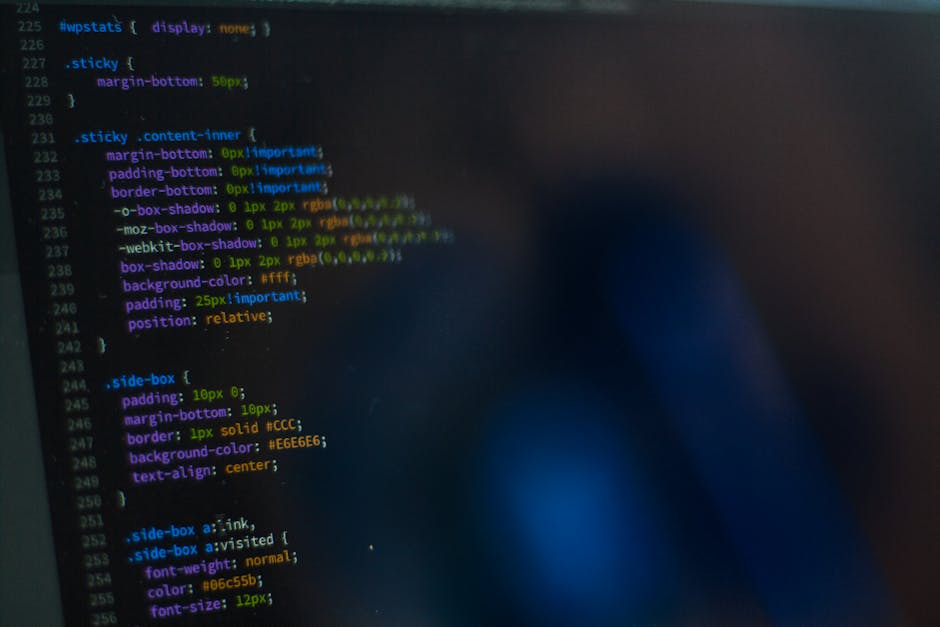 A close-up view of a computer screen displaying lines of colorful programming code with syntax highlighting, including keywords, properties, and values in various colors such as blue, green, yellow, a